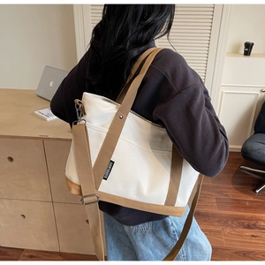 Detail of minimalist beige canvas tote bag showing thick fabric and khaki webbing trim