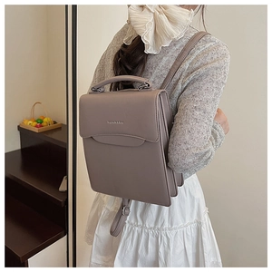 Detail of matte leather texture and silver embossed logo on a grey-purple handbag