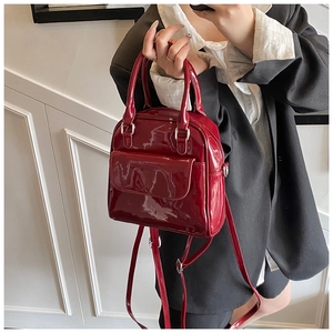Close-up of a glossy burgundy patent leather mini backpack with silver metal hardware