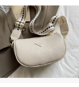 Detail view of off-white crescent pillow bag with lychee grain leather and jacquard strap