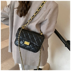 Quilted black crossbody bag with gold chain strap shown on a model in a grey blazer