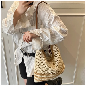 Detail shot of hollow woven tote bag with brown leather strap on model shoulder