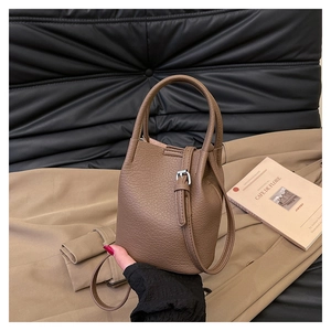 Close-up of a dark camel lychee leather bucket bag with silver metal side buckles
