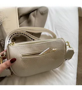 Detailed close-up of cream pebble leather pillow bag with stylish geometric wide strap