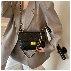 Detail shot of a black quilted crossbody bag with gold chain and metal buckle on a model