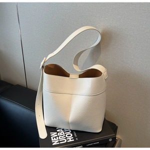 Detail of white lychee grain leather bucket bag with contrast brown interior and wide strap