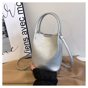 Macro view of silver bucket bag showing pebbled leather texture and dual top handles