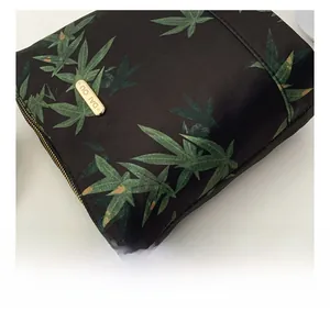 Detail of leaf pattern nylon fabric with golden metal logo plaque and zipper accents
