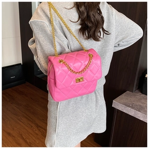 Close-up of bright pink quilted crossbody bag featuring gold chain and square lock
