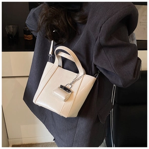 Detail of cream white leather bucket bag with metallic chain and small pouch charm