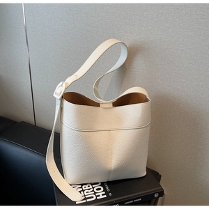 Detail of white lychee grain leather bucket bag with adjustable strap and tan interior