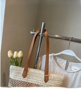 Détail d'un grand sac cabas en paille avec bandoulières en cuir marron et fermeture éclair