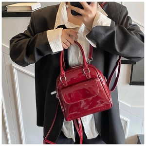 Detailed view of red patent leather handbag with adjustable strap and front flap pocket