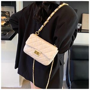 Detail of quilted beige crossbody bag with gold chain strap on model in black suit