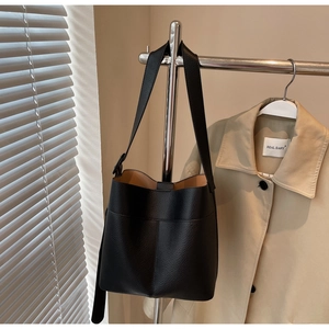 Detail of black lychee grain leather bucket bag with wide strap on silver hanger