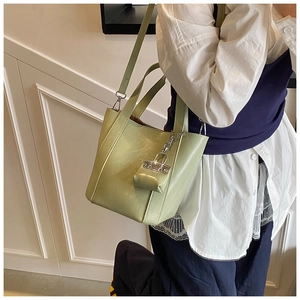 Detail of green bucket bag featuring premium PU leather texture and silver chain charm