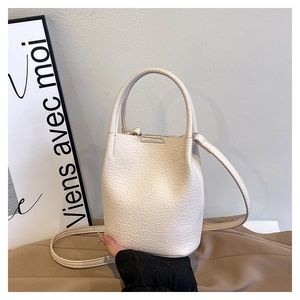 Close-up of off-white lychee pattern leather bucket bag with elegant round handles
