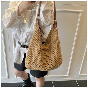 Close-up of woven straw beach bag with brown leather strap and gold ring detail