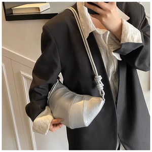 Chic silver metallic crescent bag with vertical stitching shown as a crossbody on model