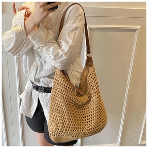 Detail of hollow woven beach bag featuring rich texture and brown leather strap