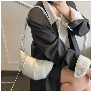 Detail of silver metallic crescent bag with vertical stitching and knotted shoulder strap