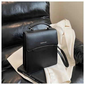 Detail of the black leather textured flap with FASHION & BAG lettering and metallic clasp