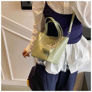 Detail of light green bucket bag with mini pouch charm and adjustable shoulder strap