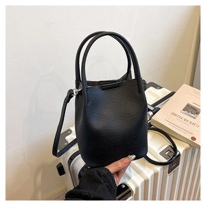 Close-up of black lychee grain leather bucket bag with dual handles and long strap