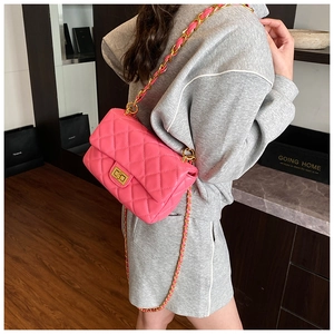 Detail of bright pink quilted crossbody bag with gold square twist lock and chain strap