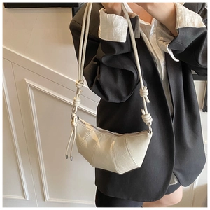 Close-up of ivory crescent bag featuring pleated details and knotted shoulder strap