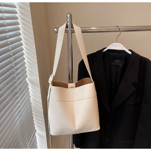 White pebbled leather bucket bag with brown lining and adjustable shoulder strap detail