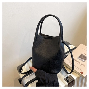Detail of black lychee grain leather bucket bag featuring dual handles and adjustable strap