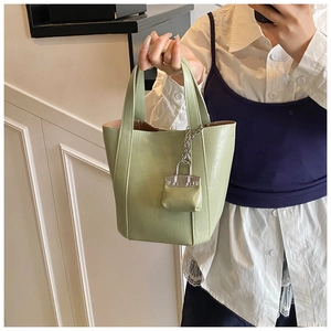 Detail of light green bucket tote bag with mini purse charm and silver chain link handle
