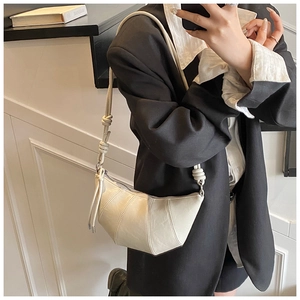 Close-up of cream crescent crossbody bag with stylish knot detail on shoulder strap