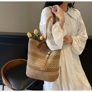 Détails du sac cabas en paille avec bandoulières en cuir marron et pompon décoratif