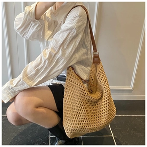Detail of hand-woven straw shoulder bag with large eyelet knit and brown leather strap