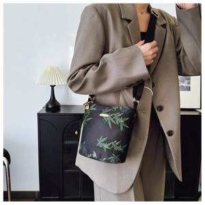 Close-up of waterproof nylon crossbody bag with green leaf pattern and golden logo
