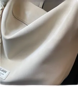 Detail of soft cream leather tote bag featuring fine lychee texture and brand logo patch
