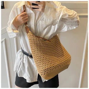 Detail of hand-woven hollow straw bag with premium brown leather strap and mesh texture