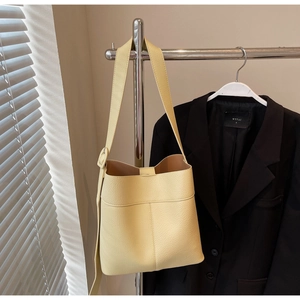 Close-up of a pale yellow lychee texture bucket bag hanging in a stylish setting