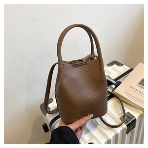 Detailed macro view of brown leather bucket bag with top handle and strap on a suitcase