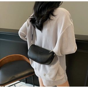 Detail of black pebbled leather half-moon bag with gold hardware worn over the shoulder