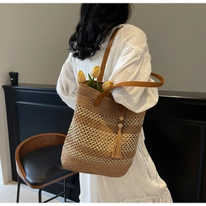 Détail d'un sac cabas en paille tissé à la main avec anses en cuir et pompon décoratif