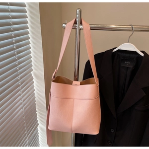 Close-up of pink litchi grain leather bucket bag with wide shoulder strap detail
