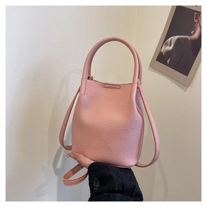 Detail of pink bucket bag featuring lychee texture leather and adjustable shoulder strap