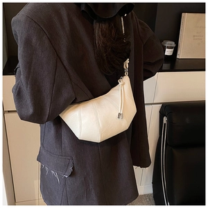 Detail of off-white crescent bag with stitched segments and metal-tipped drawstring straps