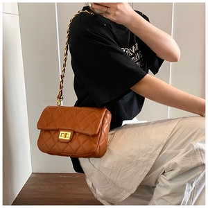 Brown quilted crossbody bag with gold chain strap worn by model in everyday setting