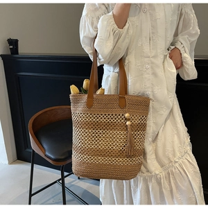 Vue détaillée du sac cabas en paille tressée avec franges décoratives et anses en cuir