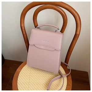 Detail of mauve leather handbag with silver hardware on a rustic wooden chair