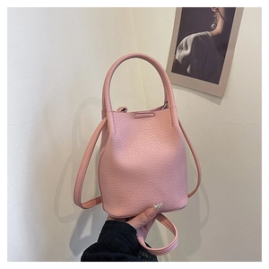 Close-up of pink bucket bag with leather lychee texture and top handle for women